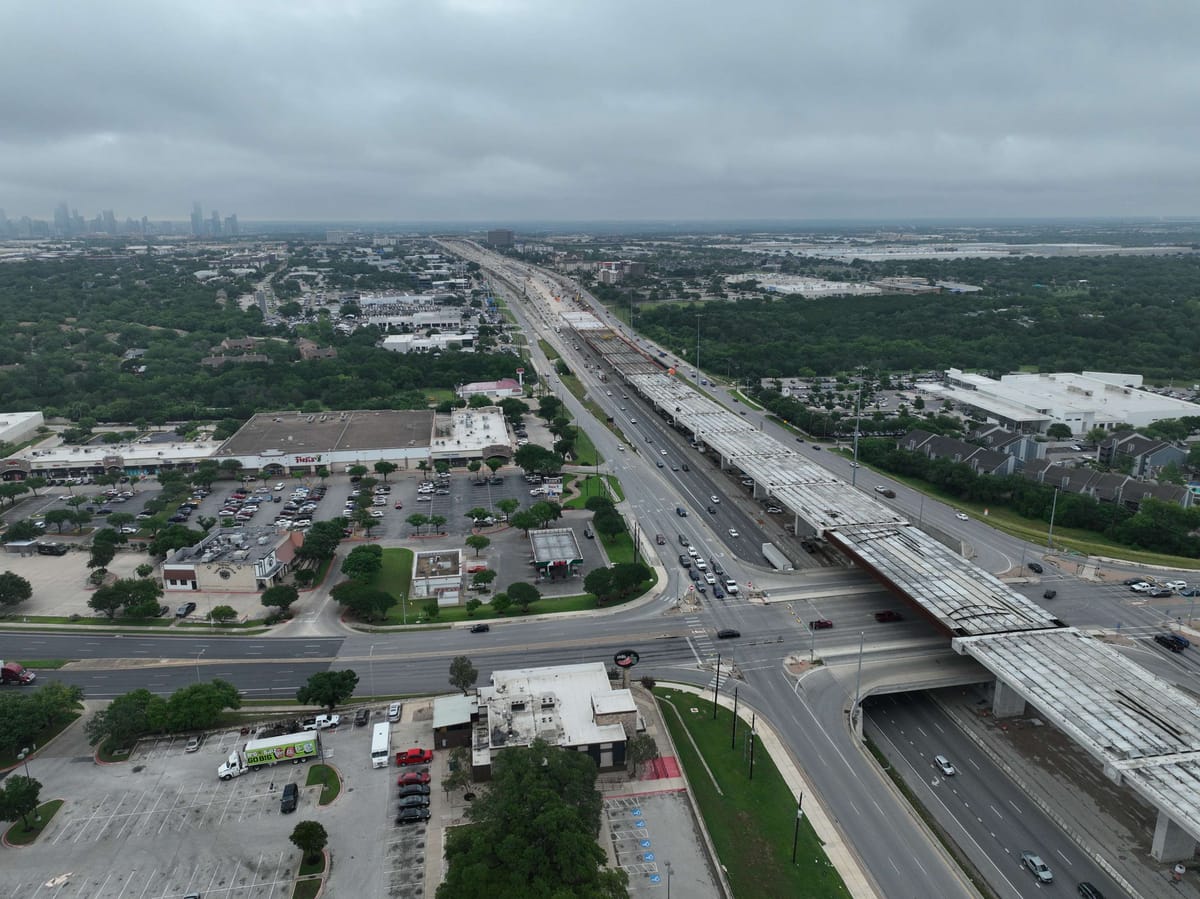 Aerial photo of I-35 in South Austin with new overpass construction alongside the main lanes and the downtown skyline in the distance.